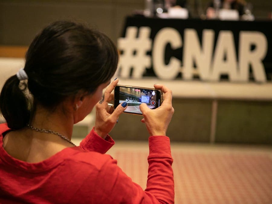 Una asistente fotografía con el celular las letras del #CNAR2023.